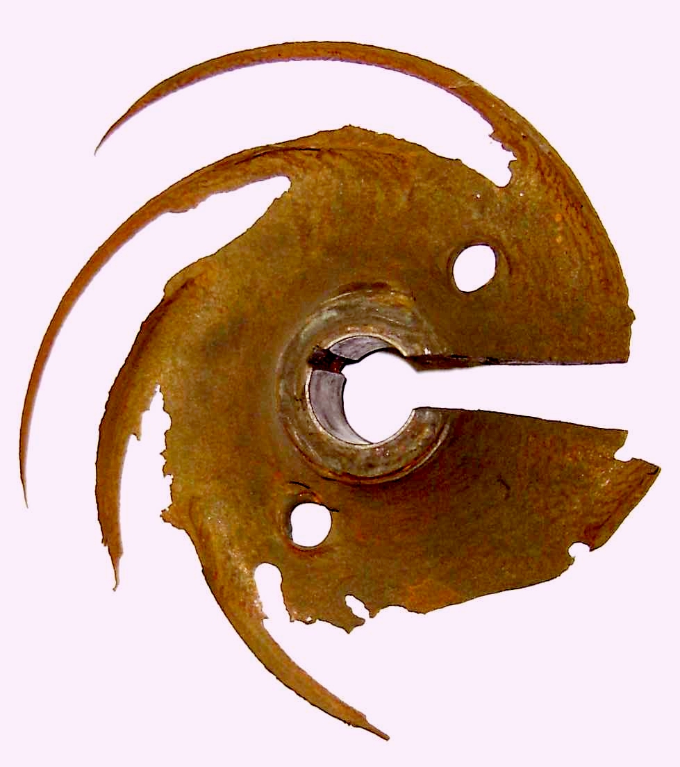 A severely damaged cast-iron water-pump impeller with visibly missing metal along its outer edge and vanes